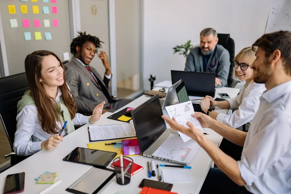 Un espace de travail contemporain où des mains examinent des données marketing sur un ordinateur portable et des documents papier.