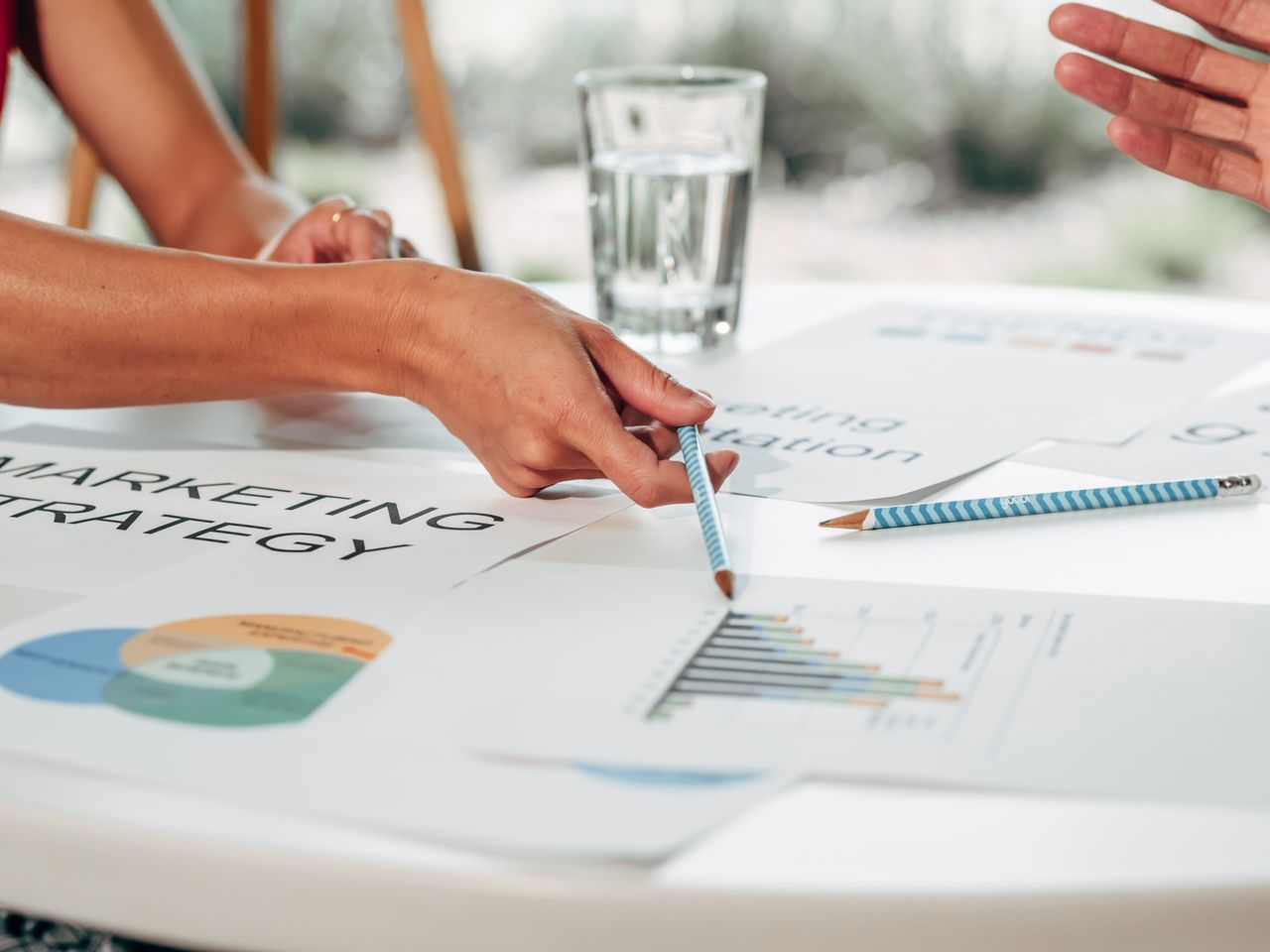 Hands engaged in marketing strategy discussion around charts in an office environment.